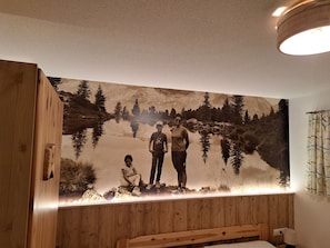 Experience the tranquility of nature in this serene retreat, featuring a stunning mural and a comfortable bed with a wooden headboard.