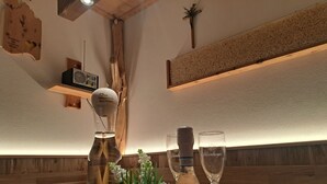 A wooden table with a bottle of Brilla Rose wine, a glass, and a decorative centerpiece. - Haus Carmen, family-friendly 4 Edelweiss holiday apartment with BergePlus program (St. Gallenkirch)