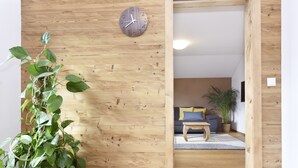 Een houten interieur met een klok, een bank en een plant.