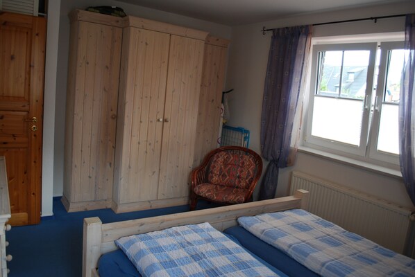 Ein Schlafzimmer mit einem Doppelbett, einem Holzschrank und einem Stuhl.