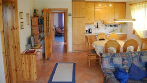 A cozy kitchen with wooden cabinets, a dining table with chairs, and a blue rug on the floor. - Family friendly, comfortable, cozy apartment to 5 persons (Schönberg)