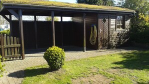A wooden building with a covered porch, a small bush, and a paved pathway. - Family friendly, comfortable, cozy apartment to 5 persons (Schönberg)