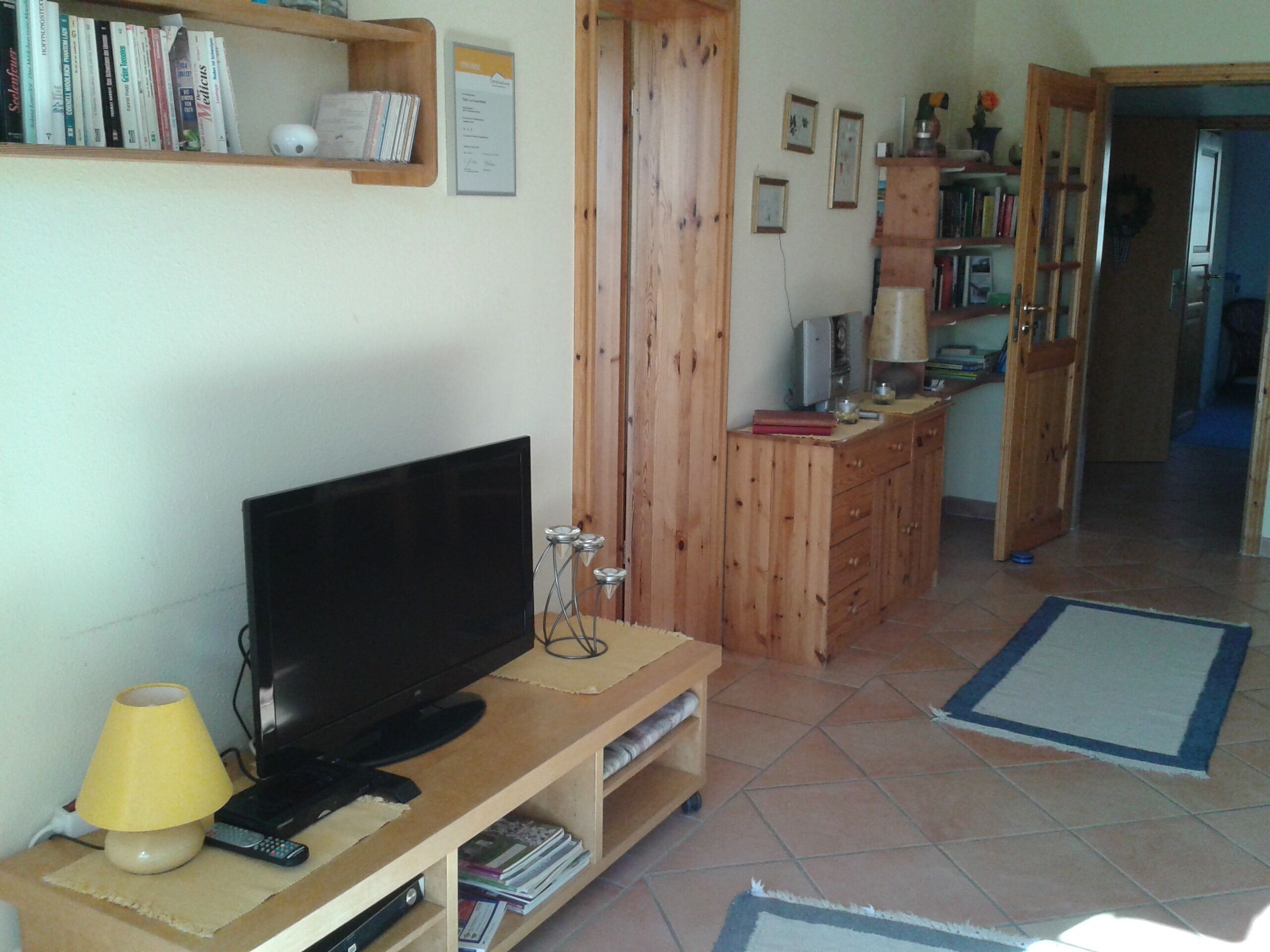 Ein Wohnzimmer mit Fernseher, Lampe und Bücherregal.