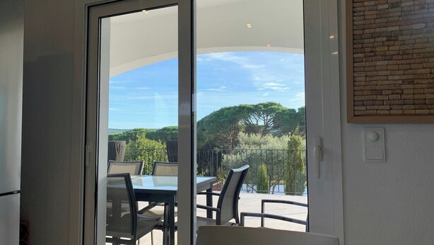 A room with a sliding glass door leading to an outdoor patio with a table and chairs.