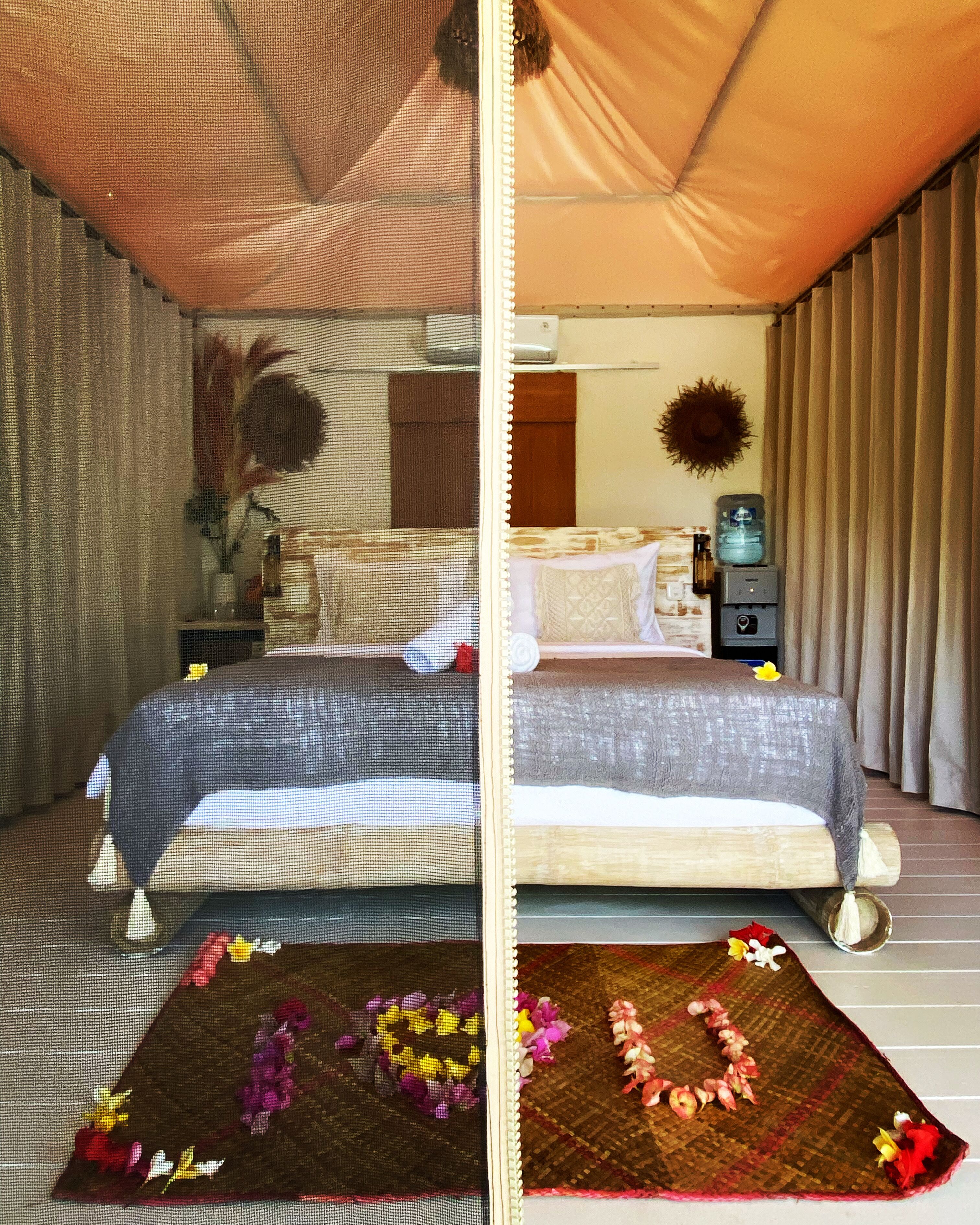 A bed with a grey blanket and pillows, a water dispenser, and a small table with a vase of flowers.