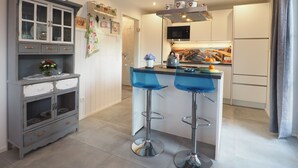 Uma cozinha moderna com uma ilha central, banquetas e um micro-ondas.