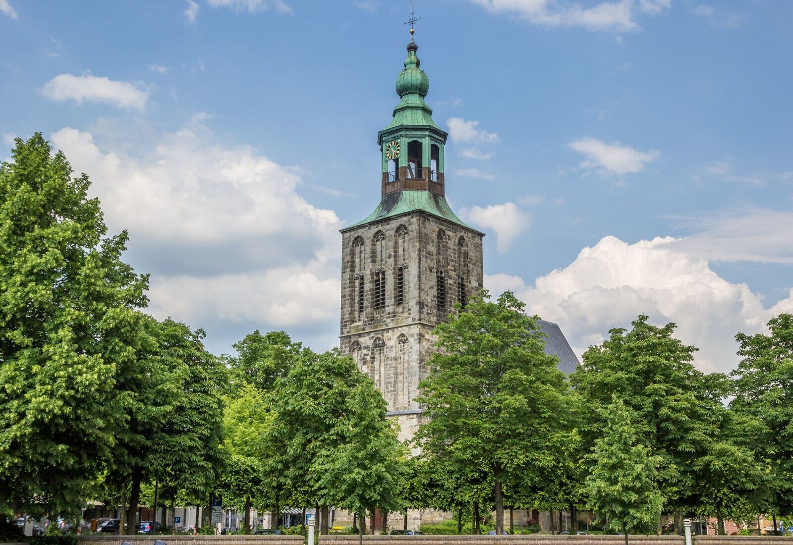 A historic tower with a clock, surrounded by lush green trees.