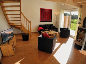 A spacious living area with a wooden staircase, a black sofa, a coffee table, and a fireplace.