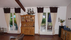 A room with a wooden cabinet, a leather sofa, and a dining area with chairs and a table.