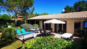 A house with a tiled roof, a patio with outdoor furniture, and a well-maintained garden.