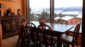 Un espace repas doté d’une grande fenêtre donnant sur des montagnes enneigées.