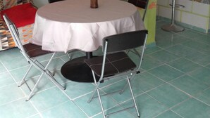 A dining area with a round table, four chairs, a refrigerator, and a wall-mounted picture.