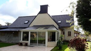 Ein Haus mit Anbauten, einem Garten und einem geneigten Dach.