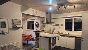 Eine moderne Küche mit einer zentralen Kochinsel, einem Essbereich mit Tisch und Stühlen sowie einem Fenster mit Blick.