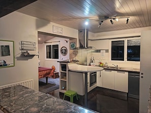 A modern kitchen with a central island, a dining area with a table and chairs, and a window with a view.