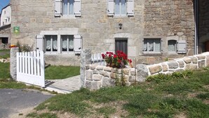 A stone building with multiple windows and a white gate. - House completely renovated character located 1 km from the Gorges du Bès (Arzenc-d'Apcher)