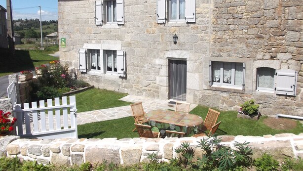 A stone building with a lawn, outdoor seating, and shutters. - House completely renovated character located 1 km from the Gorges du Bès (Arzenc-d'Apcher)