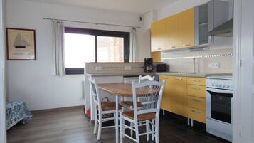 Een keuken met een eettafel, stoelen, een koffiezetapparaat en een kookplaat.