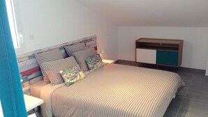 A bedroom with a bed, a nightstand, a dresser, and a window with curtains.