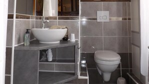 A modern bathroom with a large mirror, a sink, a toilet, and a shower area.