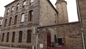 A stone building with a traditional architectural style, featuring a prominent tower and multiple windows.