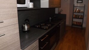 A modern kitchen with a microwave, kettle, stove, and wooden cabinets.