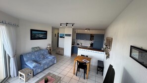 A compact living space with a sofa, a small table, a kitchenette, and a dining area. - Apartment T 2 PERROS GUIREC PANORAMIC SEA VIEW ROSE GRANITE COAST (Perros-Guirec)