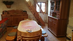 Een eetruimte met een houten tafel, stoelen, een bank en een kast.