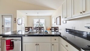 A modern kitchen with white cabinets, a black countertop, and a stainless steel sink. - A secluded 3 bedroom, 2 bath Gulf view home nestled in lush tropical vegetation (St George Island)