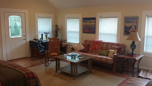 A cozy living room with a plaid sofa, a wooden coffee table, and a dining area with a table and chairs. - Beautiful Mountain Getaway - All Four Breathtaking Seasons! (Hendersonville)