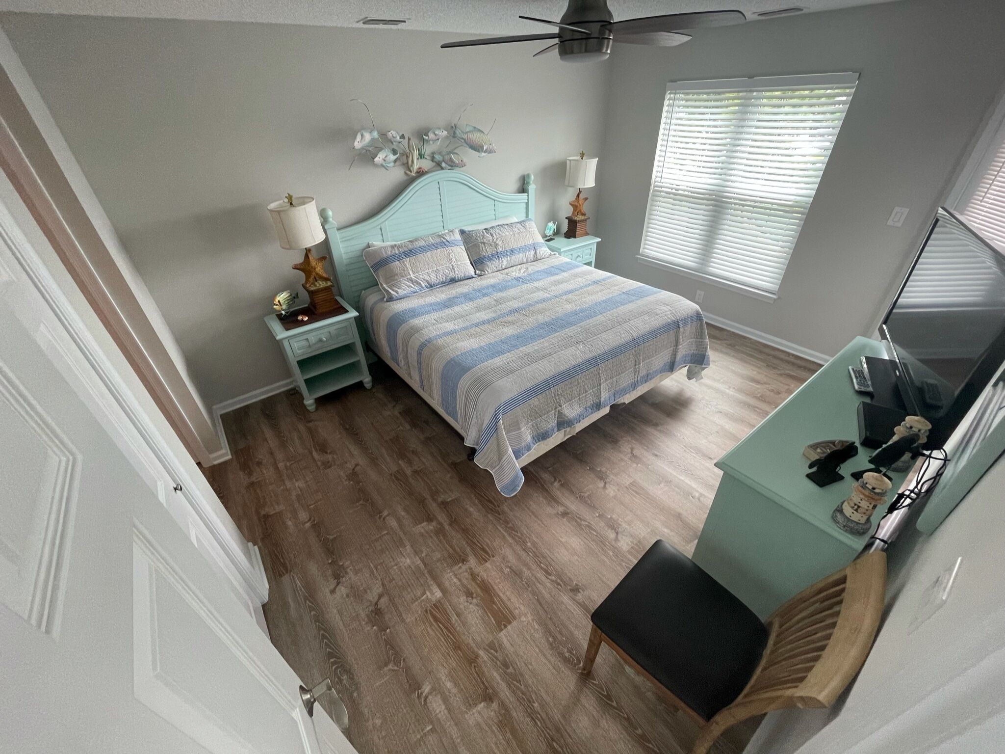 Ein Schlafzimmer mit Bett, Nachttischen, Schreibtisch und Deckenventilator.