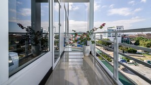Un balcon doté de grandes fenêtres, de plantes en pot et offrant une vue sur le paysage urbain.