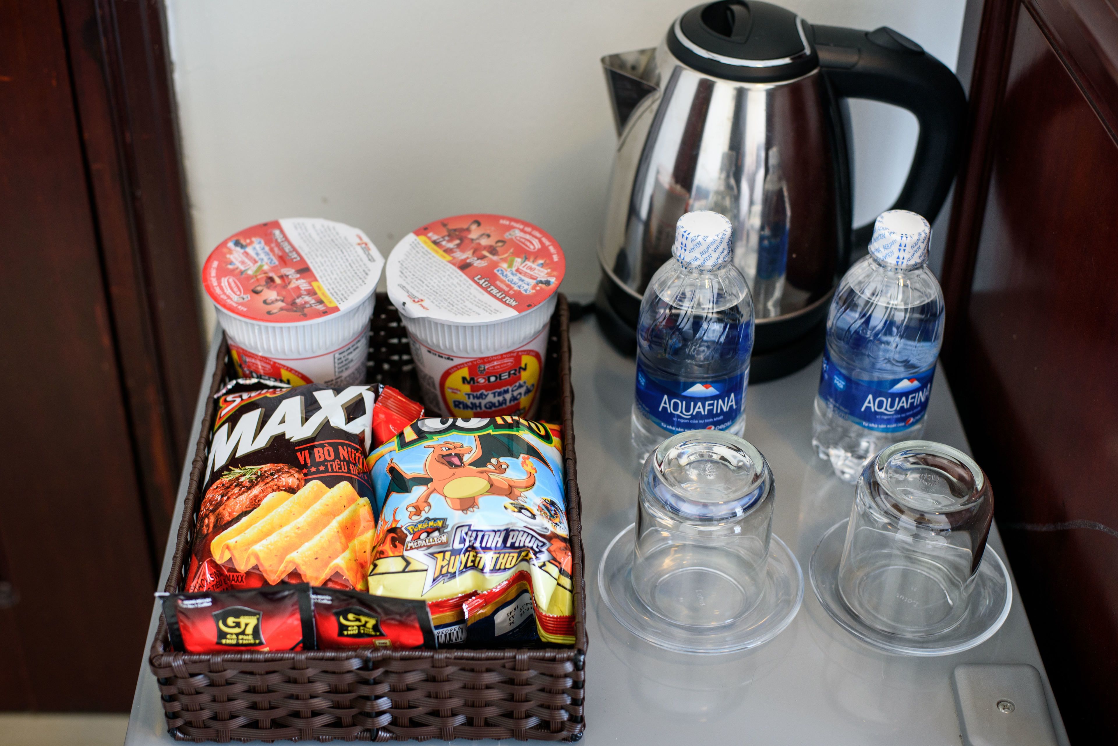 A tray with snacks, two yogurt containers, a kettle, and two water bottles.
