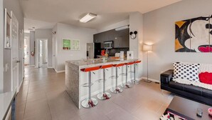 A modern kitchen with a central island, bar stools, a microwave, and a refrigerator. - Windsor Palm Resort/Pool /3 miles to Disney (Kissimmee)