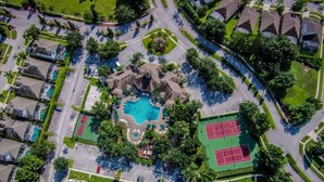 An aerial view of a residential area with a swimming pool, tennis courts, and a landscaped park. - Windsor Palm Resort/Pool /3 miles to Disney (Kissimmee)