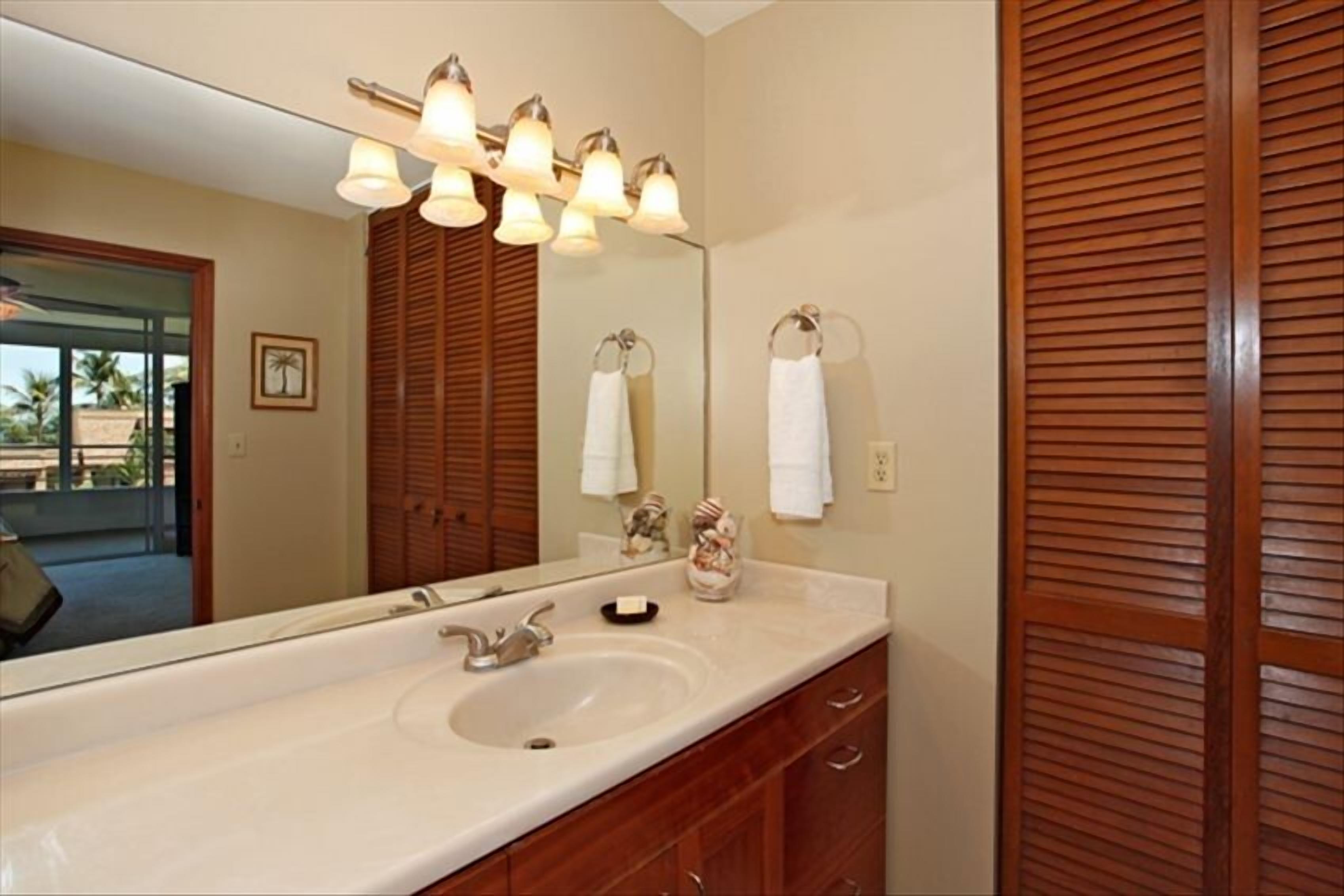 A bathroom with a large mirror, a sink, and wooden cabinets.