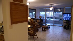 Een woonkamer met een bank, stoelen, een salontafel en een televisie.