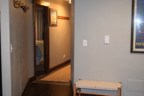 Un pasillo con un banco de madera, una puerta y una lámpara fijada a la pared.