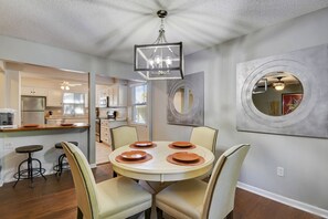 A dining area with a round table, four chairs, and a chandelier. There is a kitchen in the background with a refrigerator and cabinets. - ♥Cozy Townhome w Lux Beds♥Full Kitchen♥ Deck♥Park access two doors down♥ (Overland Park)