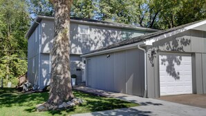 A two-story house with a garage, a tree in front, and a clear sky. - ♥Cozy Townhome w Lux Beds♥Full Kitchen♥ Deck♥Park access two doors down♥ (Overland Park)