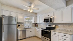 A modern kitchen with white cabinets, stainless steel appliances, and a tiled backsplash. - ♥Cozy Townhome w Lux Beds♥Full Kitchen♥ Deck♥Park access two doors down♥ (Overland Park)