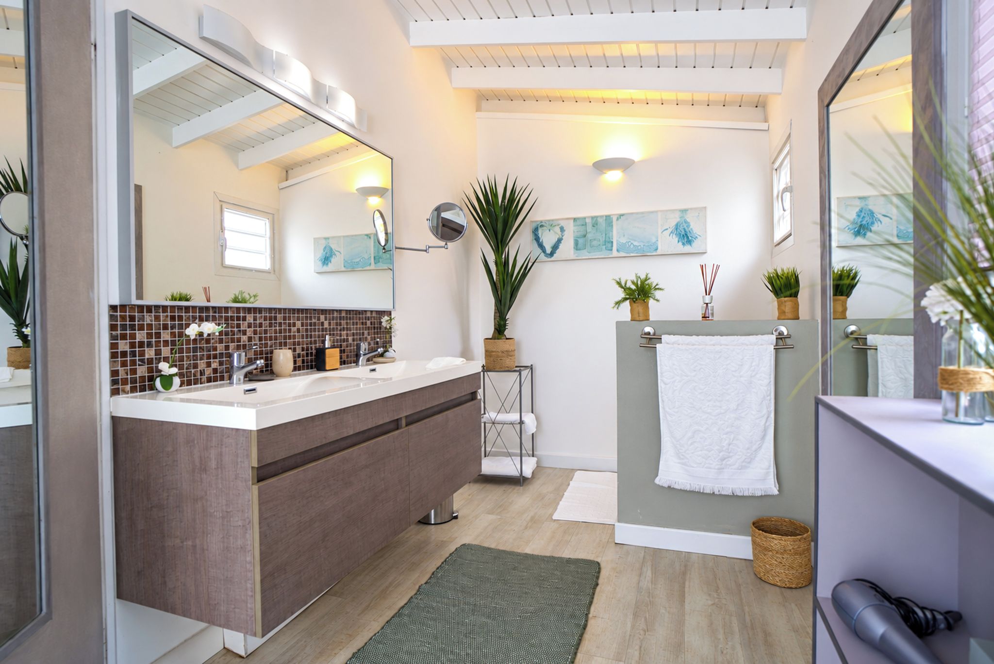 Een moderne badkamer met een grote spiegel, een wastafel met handdoekhouder, en een douchehoek.
