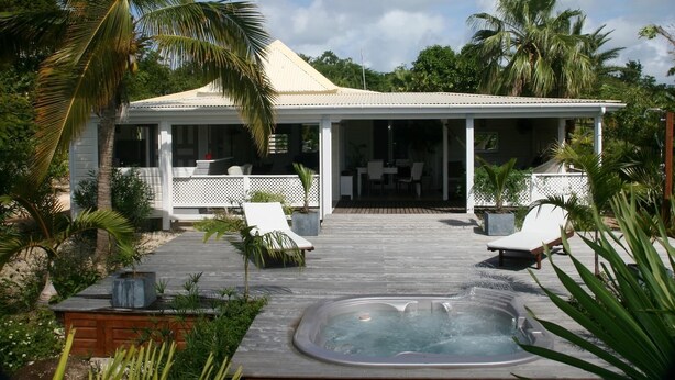 A covered outdoor area with a hot tub, lounge chairs, and a dining area. - Guest-House In A Palmgrove For A Couple. Space, Privacy And Silence (Saint Martin)