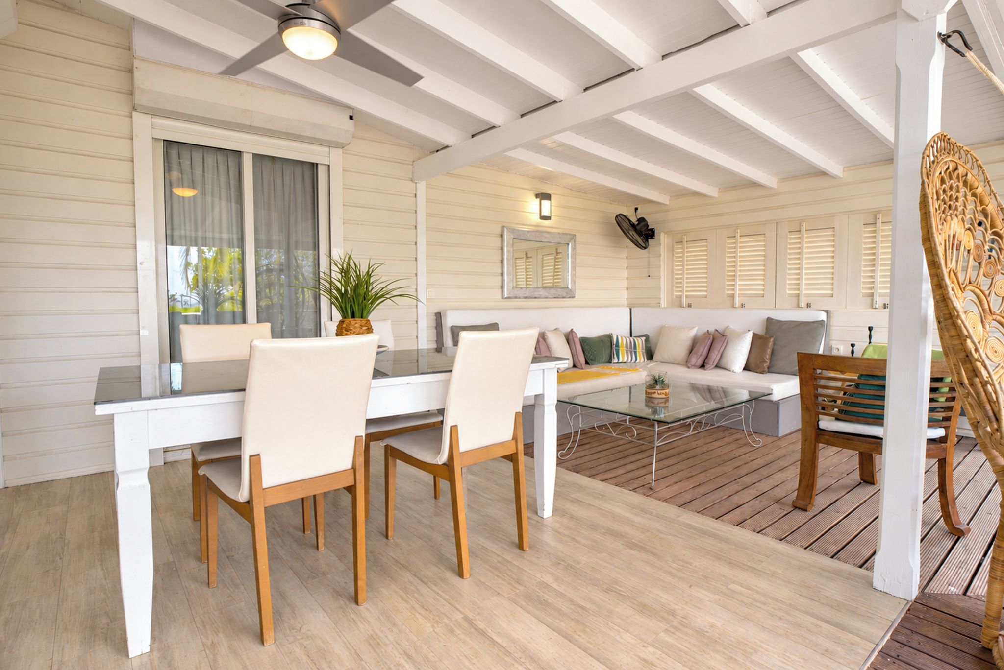 Une pièce comprenant une table à manger, des chaises, un canapé et un fauteuil en osier.