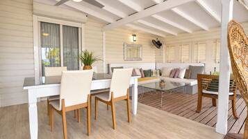 Une pièce comprenant une table à manger, des chaises, un canapé et un fauteuil en osier.