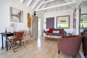 A modern living room with a dining area, a sofa, and a coffee table. - Guest-House In A Palmgrove For A Couple. Space, Privacy And Silence (Saint Martin)