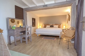 Ein Schlafzimmer mit Bett, Nachttischlampen, einem Schminktisch, einem Stuhl und einem Spiegel.