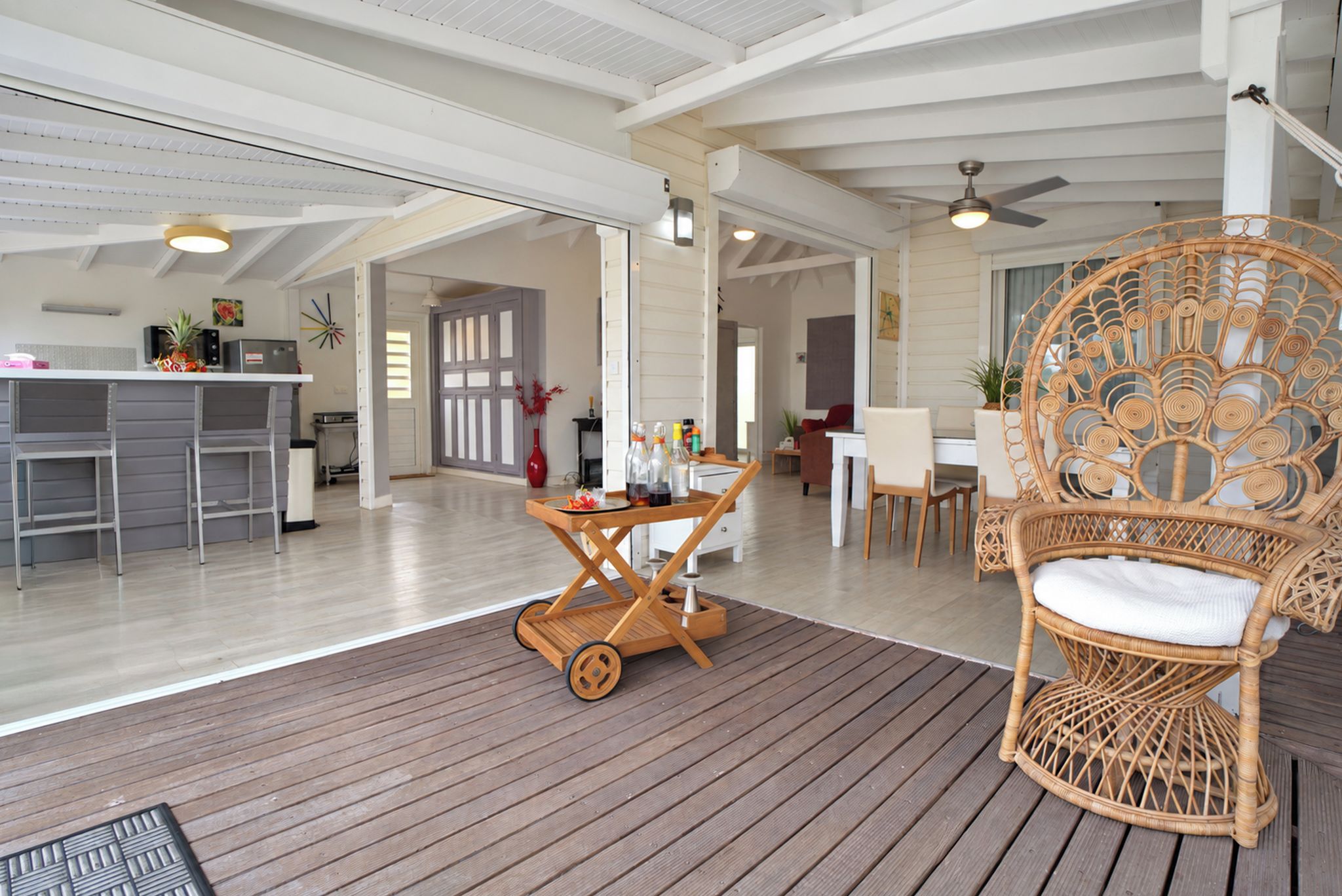 A spacious living area with a wooden deck, a wicker chair, and a dining table.