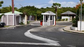A gated residential area with a small gazebo, a covered outdoor seating area, and a street with a curved road.