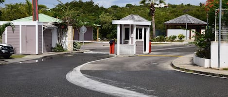 A gated residential area with a small gazebo, a covered outdoor seating area, and a street with a curved road.